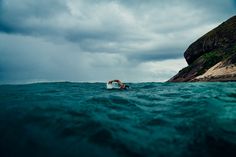 a man riding a surfboard on top of the ocean next to a rocky cliff