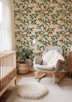 a baby's room with a rocking chair, crib and large wallpaper