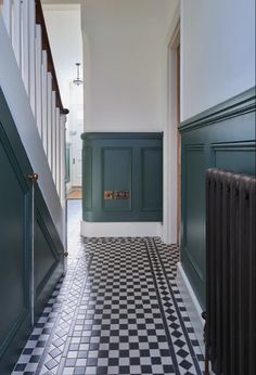 a hallway with black and white checkered flooring, green painted walls and stairs