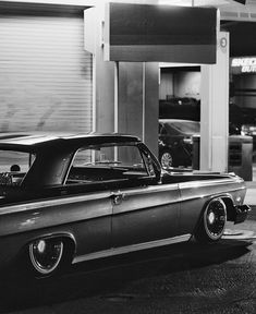 an old car parked in front of a garage