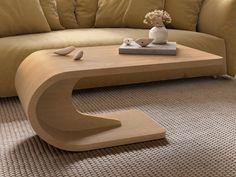 a wooden table sitting on top of a carpeted floor next to a beige couch