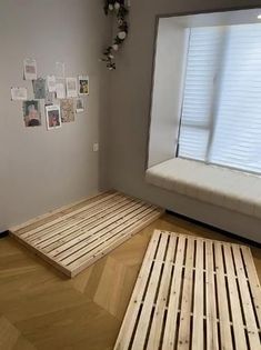 a room with wooden flooring and pictures on the window sill, next to a bench