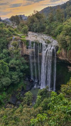 a large waterfall surrounded by lush green trees