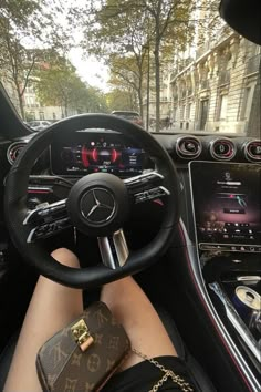 a person sitting in the driver's seat of a car with their feet on the steering wheel