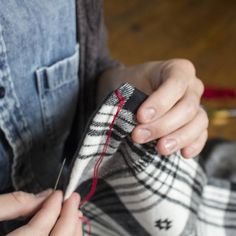 a person is sewing something on a pair of socks that are being held by someone's hands