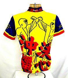 a yellow shirt with red, blue and white designs on the front is sitting on a mannequin