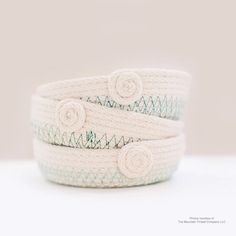 three white and blue bracelets with flowers on them sitting on top of each other