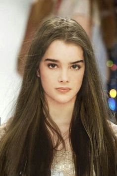 a woman with long brown hair is looking at the camera