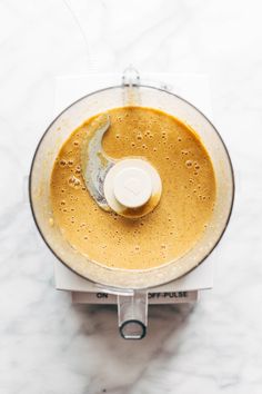 an overhead view of a food processor with liquid in it on a marble counter top