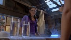 a woman standing in front of a table filled with water