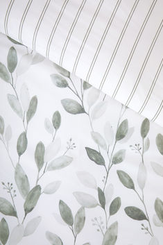 a close up view of a bed sheet with leaves and stripes on the coverlet