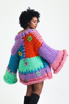 a woman is wearing a colorful sweater and boots