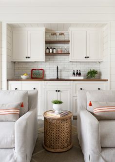 a living room with two chairs and a table in front of the couches on the floor