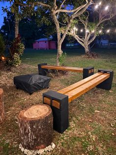 a wooden bench sitting in the middle of a park next to a tree stump with lights on it