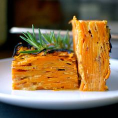 a piece of food on a plate with a sprig of rosemary next to it