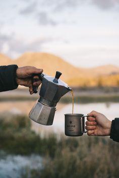 two people holding coffee cups and pouring them into each other