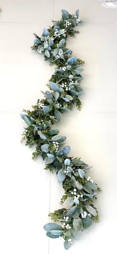 a white tile floor topped with lots of green leaves and flowers on it's side