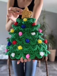 a woman holding a crocheted christmas tree decoration