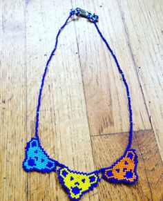 a beaded necklace with two cats on it sitting on top of a wooden floor