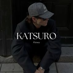 a person sitting on the ground wearing a hat and jacket with words that read, katsuuro victory