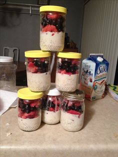 four jars filled with fruit and yogurt sitting on top of a kitchen counter