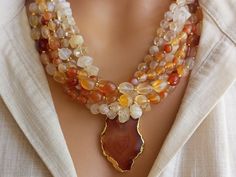 Meet our elegant Quartz - Agate Beaded Necklace, a collection of unique handcrafted jewelry that is sure to attract attention! This eye-catching necklace creates a striking visual with large gem stones in different shades of orange. Perfect as a gift for a beloved mother or wife, this statement chunky multi-strand natural stone summer accessory will add a bohemian touch to any outfit. CARE INSTRUCTIONS: To keep your necklace looking its best, avoid exposing it to harsh chemicals or excessive moisture. To clean, wipe gently with a soft, damp cloth. To prevent any damage or tarnishing, store your necklace in a cool, dry place when not in use. DIMENSIONS: - Length: 18 inches. - Pendant Size: 1 inches. - Beads: 4-12 mm. ABOUT ORDERS: * All orders will be shipped to the shipping address you pro Handmade Elegant Agate Beads And Cabochons, Elegant Amber Agate Beaded Necklaces, Elegant Agate Beaded Necklace With Stones, Handmade Elegant Agate Gemstones, Elegant Handmade Agate Gemstones, Elegant Agate Crystal Necklace With Faceted Beads, Elegant Carnelian Beaded Necklace With Natural Stones, Elegant Beaded Necklace With Carnelian Stones, Handmade Carnelian Beaded Necklaces In Elegant Style