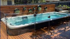 an outdoor hot tub with glass doors on the sides and wooden decking around it