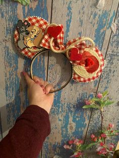 a person is holding onto a mickey mouse ears headband with hearts on it,