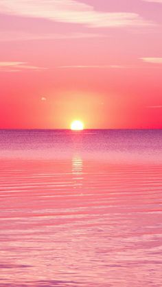 the sun is setting over the ocean with two surfers in the water on their surfboards