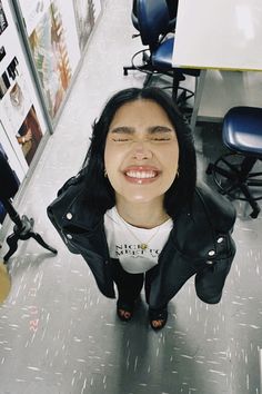 a woman with her eyes closed standing in the middle of an office space smiling at the camera