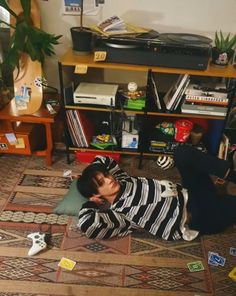 a young boy laying on the floor in front of a book shelf with many stickers all over it