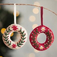 two ornaments hanging from a tree with lights in the background