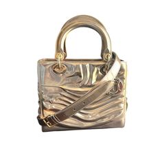 Description:  -Christian Dior Lady Art Bag  -Limited Edition by Jason Martin  -Gold and metallic patent leather  -Gold tone hardware   -Removable and adjustable shoulder strap  -Zip closure  -Protective feet at base  Authenticity: All items are guaranteed 100% authentic.  - Authenticity card included  -CD stamped zipper pull -Dior charms -Hardware stamped CD  Details:  Condition: SA2 EXCEPTIONAL (see condition rating below)Color: Gold**Color may vary by monitor or device. Please contact us for s Luxury Leather Shoulder Bag With Glossy Finish, Designer Patent Leather Bag With Glossy Finish, Luxury Patent Leather Bags For Formal Occasions, Luxury Shoulder Bag With Glossy Finish And Double Handle, Elegant Double Handle Shoulder Bag With Glossy Finish, Designer Patent Leather Bag With Detachable Strap, Luxury Silver Shoulder Bag With Gold-tone Hardware, Luxury Metallic Shoulder Bag With Palladium Hardware, Designer Metallic Bags With Gold-tone Hardware