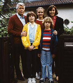 a group of people standing next to each other in front of a fence and house