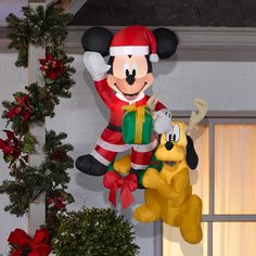 mickey mouse and pluto balloon in front of christmas decorations