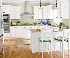 a kitchen with white cabinets and green tile on the backsplash is pictured in this image