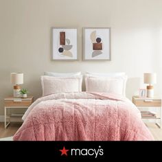 a bed with pink comforter and pillows in a white room next to two pictures on the wall