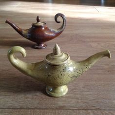 two small teapots sitting on top of a wooden table next to each other