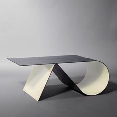 a modern table with curved edges and an unusual design on the top, against a gray background