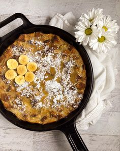 a skillet with bananas and powdered sugar on top