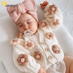 a baby wearing a pink bow laying on top of a bed