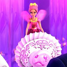 a barbie doll sitting on top of a pink object in front of a purple background