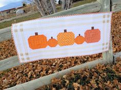 an orange and white pumpkin quilt hanging on a fence