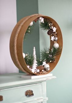 a round mirror sitting on top of a dresser next to a christmas tree and pine cones