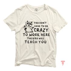 Introducing our hilarious "You Don't Have to Be Crazy to Work Here, the Kids Will Teach You" t-shirt, featuring a playful raccoon illustration! Perfect for teachers who understand the wild and unpredictable nature of the classroom, this shirt combines humor with a touch of truth to create a fun and relatable design. Enjoy comfort and style with this unisex jersey short sleeve tee. Made from soft, high-quality Airlume combed and ring-spun cotton, it features a vibrant print you'll love. With ribb Teacher Shirts Funny Preschool, Funny Preschool Teacher Shirts, Fun Short Sleeve T-shirt For Daycare, Fun T-shirt With Funny Print For Teacher Appreciation, Fun Graphic Print T-shirt For Teacher Appreciation, Raccoon Illustration, Pre K Teacher, Preschool Teacher Shirts, Graphic Print Short Sleeve T-shirt For Teacher Appreciation