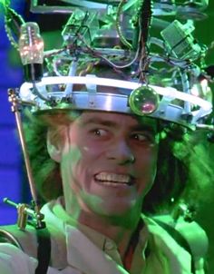 a man wearing a weird looking headpiece in front of a blue background with green lights