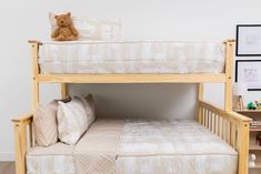 a wooden bunk bed with two pillows and a teddy bear sitting on top of it