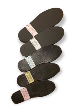 four pairs of black leather shoe insolements with tags on them, all lined up in a row