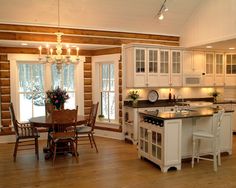 a large kitchen with white cabinets and wooden flooring, along with a center island in the middle