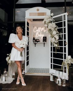 a woman standing in front of a doorway with flowers and candles on the floor next to it